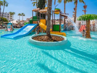 Piscina con toboganes y juegos acuáticos rodeada de palmeras y edificios de hotel.