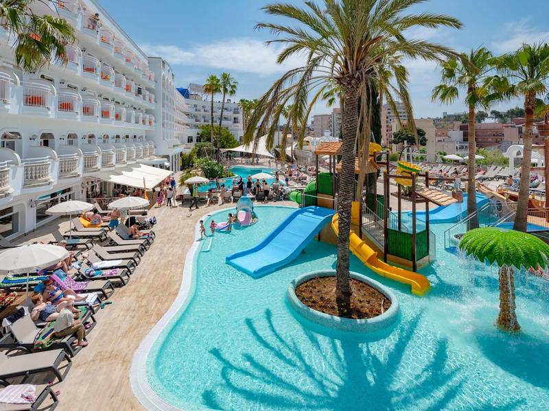 Piscina del hotel con toboganes de agua, sombrillas y tumbonas en ambiente tropical de vacaciones.