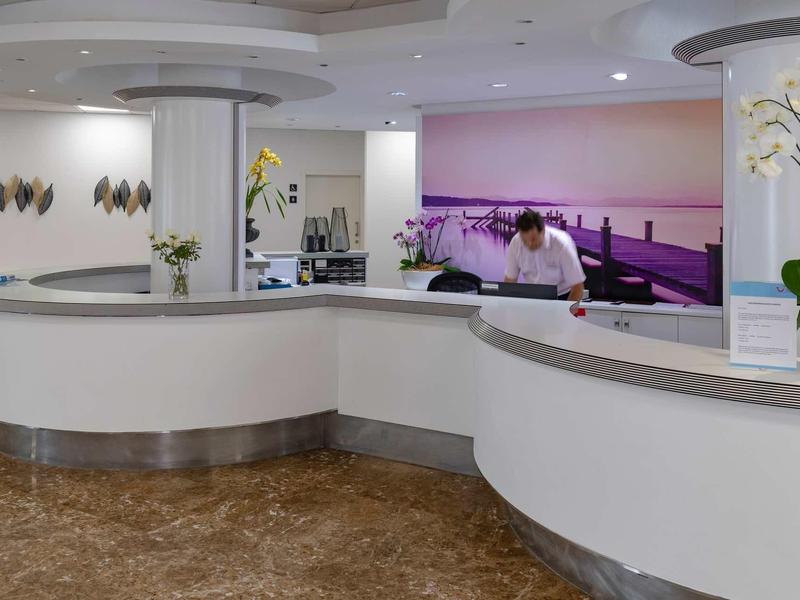 Recepción moderna en el lobby del hotel con mostrador curvo y un empleado atendiendo.