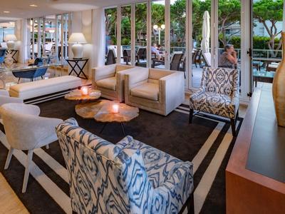 Inviting hotel lounge area with comfortable armchairs and tables, large windows overlooking the garden