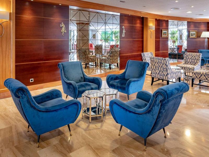 Elegantní hotelová lounge s modrými křesly a moderním dřevěným dekorem.