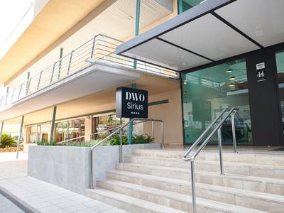 Ingresso moderno dell'hotel con ampie scale e facciata in vetro di giorno.