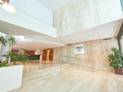 Ampia e luminosa hall d'hotel con pavimento in marmo e piante.