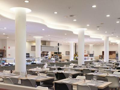 Ristorante moderno e luminoso con colonne bianche e tavoli apparecchiati in un hotel.