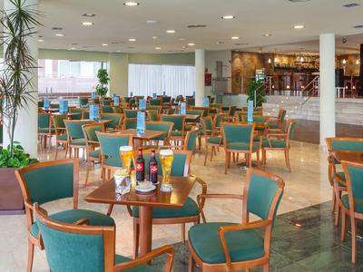 Ampia sala ristorante dell'hotel con sedie e tavoli in legno, ben illuminata e arredata in stile moderno.