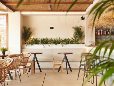 Helle Bar mit minimalistischer, natürlicher Einrichtung und Pflanzen im Hintergrund.