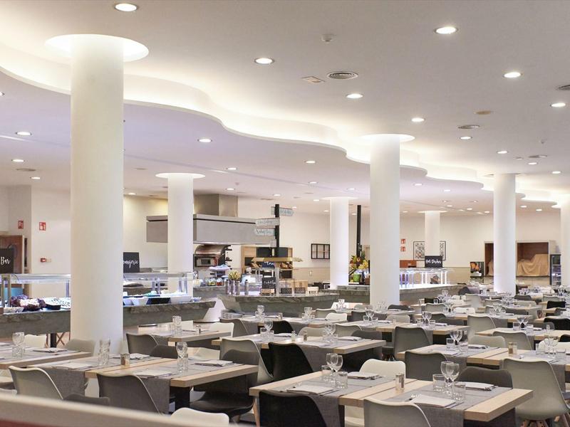 Ristorante moderno e luminoso con colonne bianche e tavoli apparecchiati in un hotel.