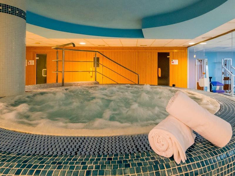 Vasca idromassaggio in una spa dell'hotel con asciugamani bianchi arrotolati come decorazione.