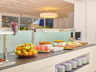 Bufet s čerstvým ovocem, pečivem a džusy v moderní hotelové restauraci.