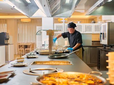 Kuchař připravuje jídlo v moderní hotelové kuchyni.