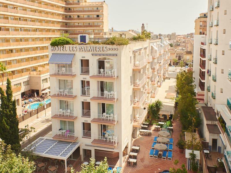 Pohled na hotel s bazénem a terasou v slunečném městském prostředí