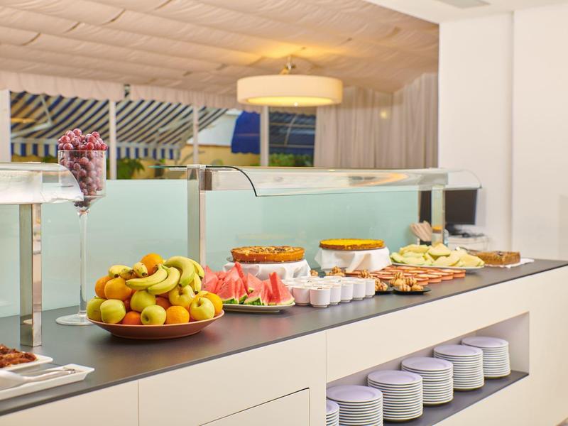 Bufet s čerstvým ovocem, pečivem a džusy v moderní hotelové restauraci.