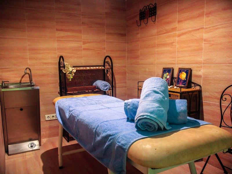 Pohodlná masážní místnost se dřevěnými stěnami, masážním stolem a uklidňující atmosférou.