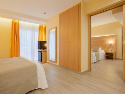 Modern eingerichtetes Hotelzimmer mit hellen Holzmöbeln und gelben Vorhängen.