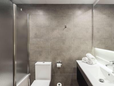 Modernes Badezimmer mit grauen Wänden, Toilette und Waschbecken mit Handtüchern.