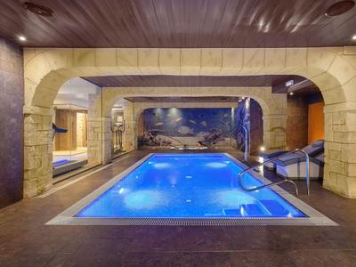 Innenpool mit stimmungsvoller Beleuchtung und mediterraner Steinarchitektur in einem Hotel.