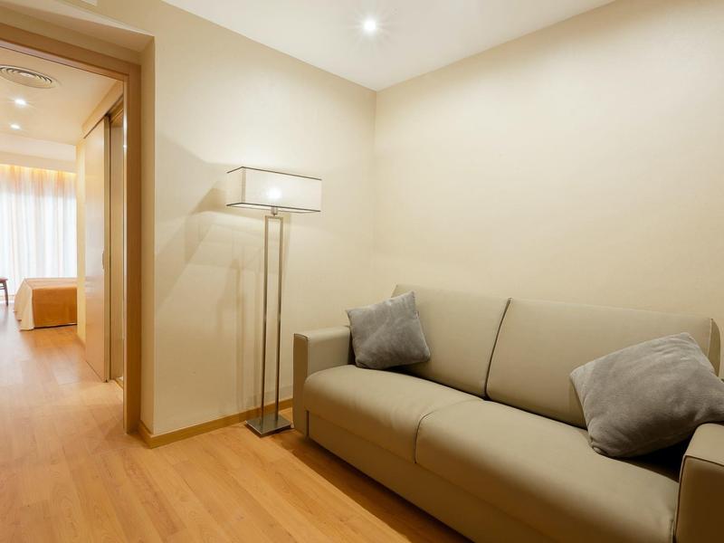 Gemütliche Sitzecke in einem Hotelzimmer mit Sofa und Stehlampe in neutralen Farben.