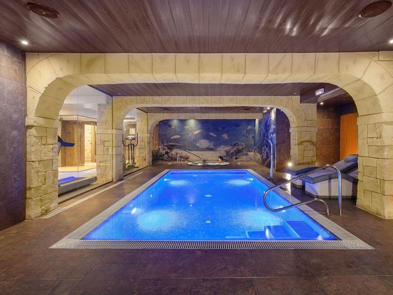 Innenpool mit stimmungsvoller Beleuchtung und mediterraner Steinarchitektur in einem Hotel.