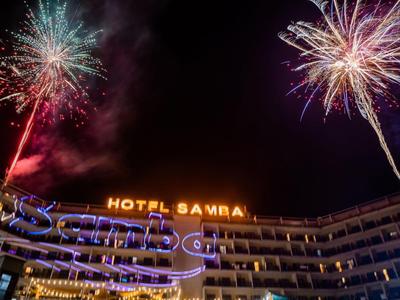 Facciata dell'hotel di notte con fuochi d'artificio colorati nel cielo.