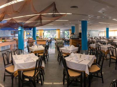 Grote, moderne eetruimte met veel gedekte tafels en blauwe zuilen.