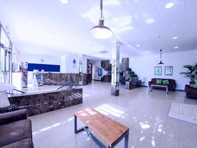 Heller Hotel-Lobbybereich mit Sitzgelegenheiten, Rezeption und moderner Beleuchtung.