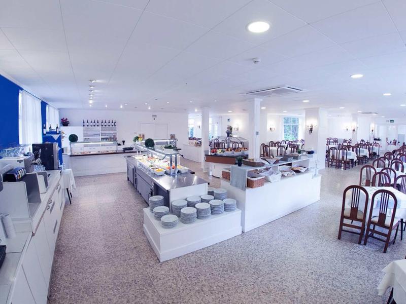 Grande sala colazioni luminosa con buffet e diversi tavoli e sedie.