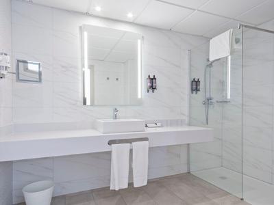 Salle de bain moderne avec deux lavabos, miroir éclairé et douche à l'italienne.