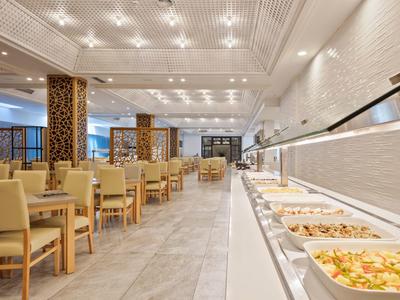 Restaurant d'hôtel moderne avec espace buffet et tables dressées dans une ambiance lumineuse.