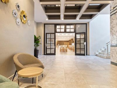 Espace lounge d'hôtel moderne avec fauteuils, tables et vue dégagée sur la salle à manger.