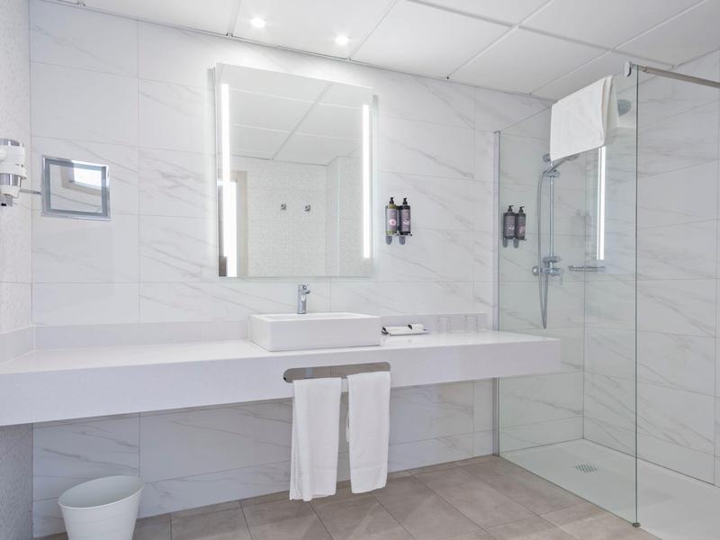 Salle de bain moderne avec deux lavabos, miroir éclairé et douche à l'italienne.