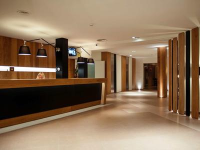 Nowoczesna recepcja hotelowa z ciepłym oświetleniem i drewnianymi akcentami.