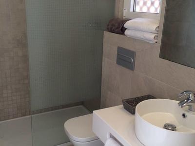 Nowoczesna łazienka z prysznicem bez brodzika, toaletą i umywalką z ręcznikami.