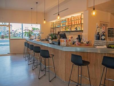 Area bar moderna in hotel con bancone in legno, sgabelli neri e lampade sospese.