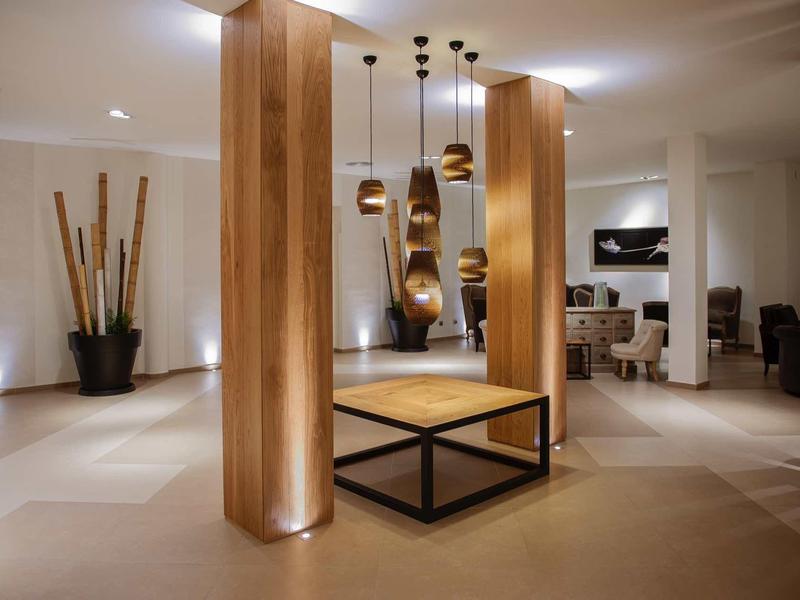 Nowoczesne lobby hotelowe z drewnianymi kolumnami i dekoracyjnymi lampami wiszącymi.