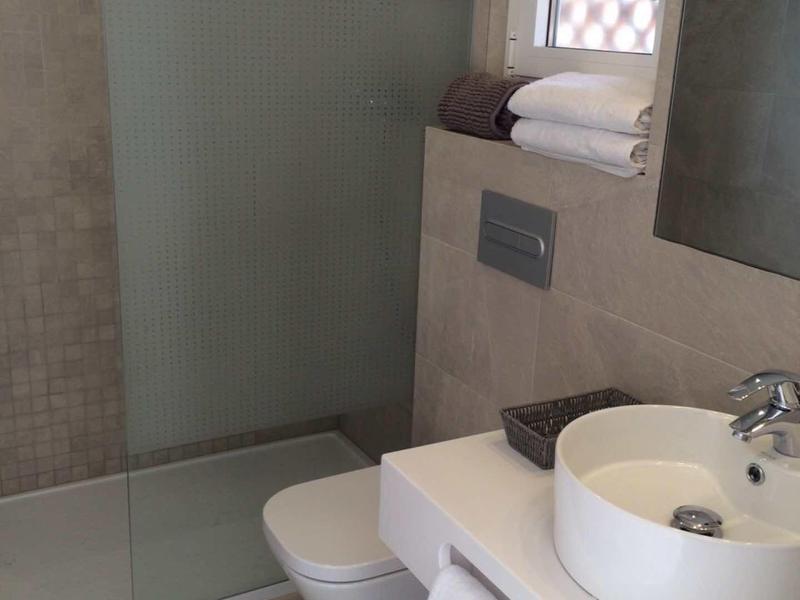 Nowoczesna łazienka z prysznicem bez brodzika, toaletą i umywalką z ręcznikami.