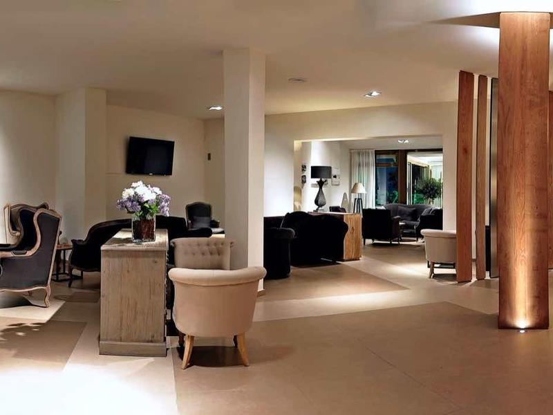 Elegancki hol hotelowy z miejscem do siedzenia, roślinami i nowoczesnym oświetleniem.