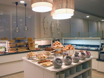 Buffet table with assorted pastries and tea in a modern hotel dining area.