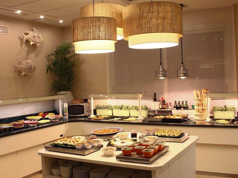 Modern hotel kitchen with central island, pendant lights, and a variety of dishes.