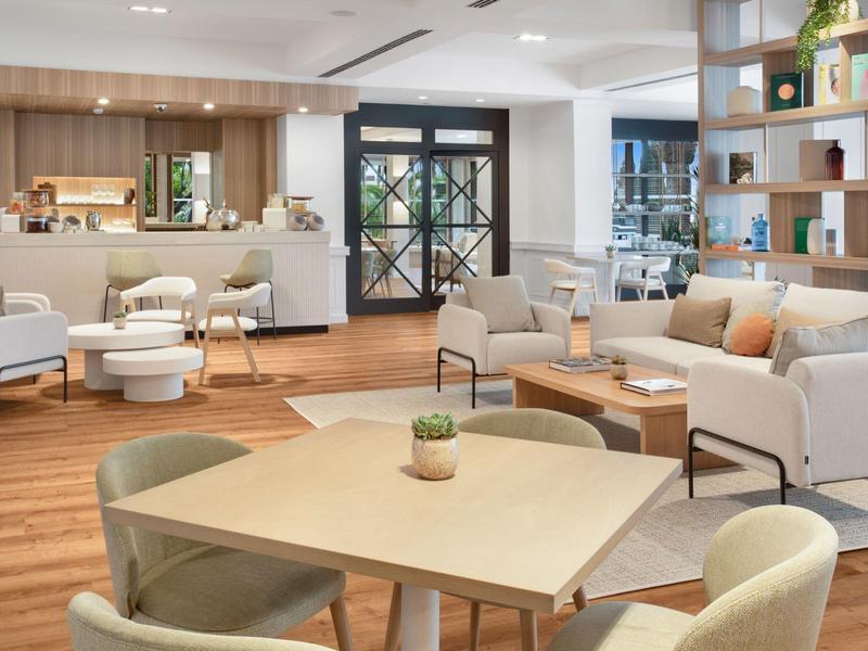 Světlý hotelový salón s moderním nábytkem a světlou dřevěnou podlahou.