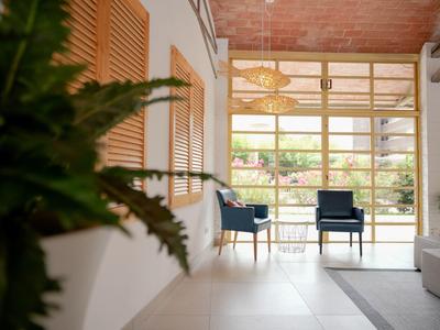 Zona lounge dell'hotel con sedie blu vicino a grandi finestre di vetro e piante interne.