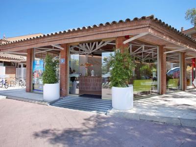 Area esterna di caffè con tetto in legno rustico e piante sotto un cielo azzurro chiaro.