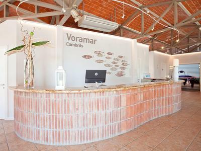 Banco della reception in un ampio hall d'hotel con design rustico in mattoni e pareti bianche.