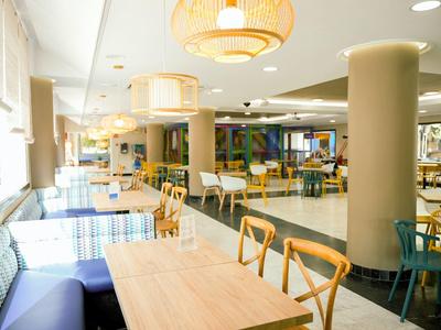 Salle à manger moderne et lumineuse avec différents espaces assis et grandes fenêtres.