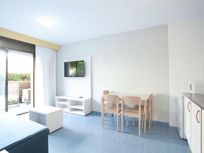 Chambre d'hôtel lumineuse avec coin repas, kitchenette, canapé et accès au balcon.