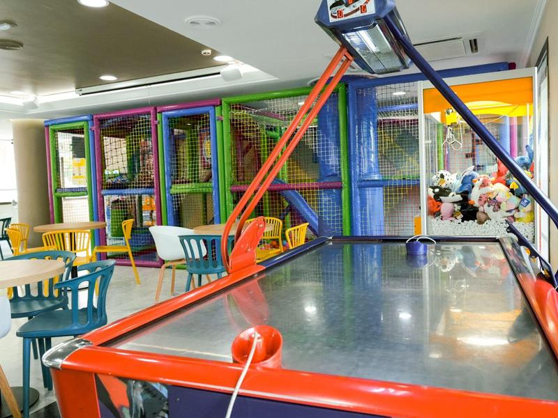 Table de air hockey dans une salle de loisirs colorée avec des chaises et une structure d'escalade.