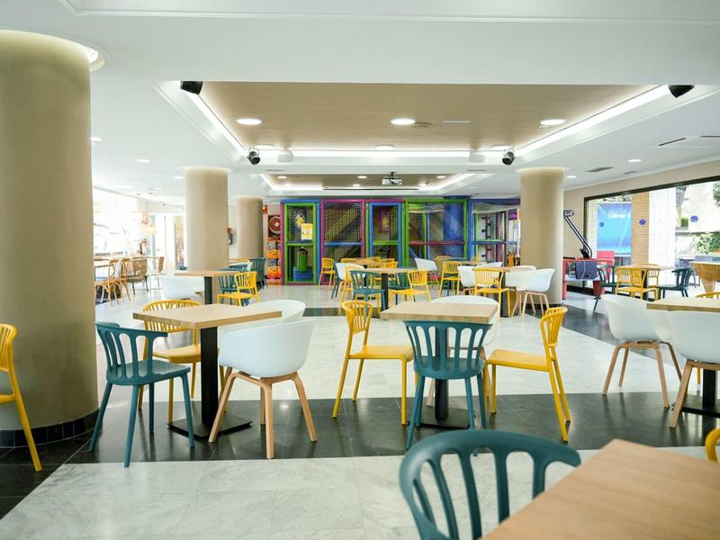 Restaurant lumineux et moderne avec des chaises colorées et de grandes fenêtres.