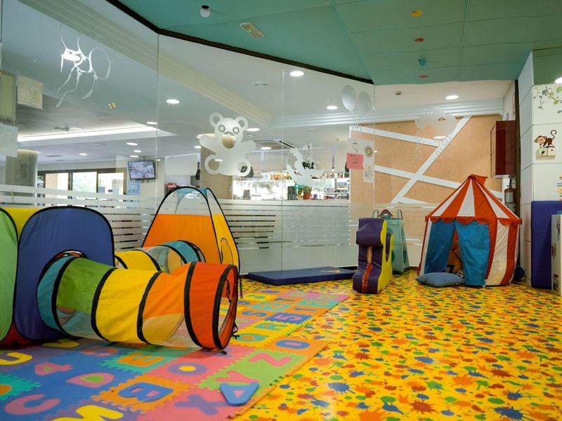 Espace de jeu coloré pour enfants avec tunnel et tente dans un hôtel ou une garderie.