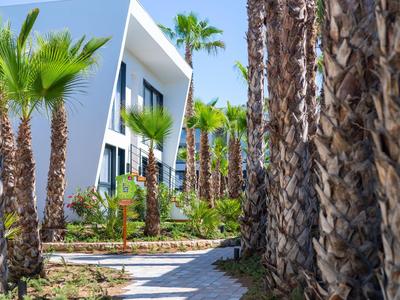 Moderne Hotelgebäude mit Palmen und gepflastertem Weg bei klarem Himmel.