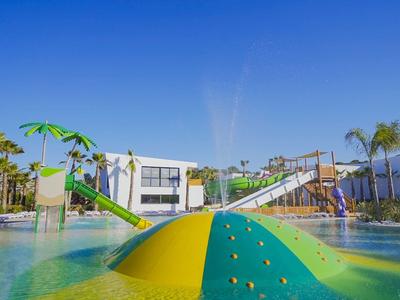 Kolorowy plac zabaw wodny z zjeżdżalniami i basenem pod niebieskim niebem.