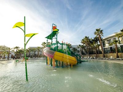 Wodne miejsce zabaw z kolorową zjeżdżalnią w płytkim basenie.